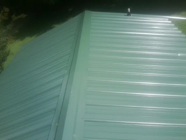 New green metal panels meeting at the ridge of a roof — Flat Roof Repair work by our crew in Salina