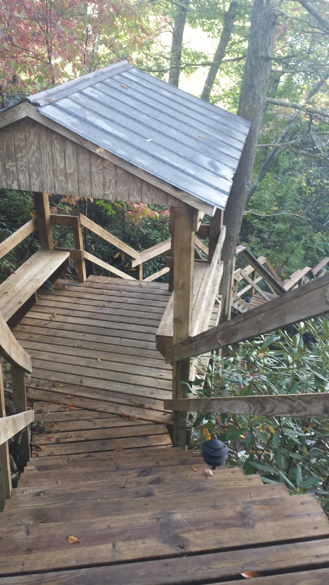 Metal roofed shelter over wooden steps on a wooded walkway — Skylight Repair & Installation work by our crew in Salina